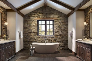 Example of a large mountain style master stone tile dark wood floor freestanding bathtub design in St Louis with furniture-like cabinets, dark wood cabinets, white walls, an undermount sink and solid surface countertops