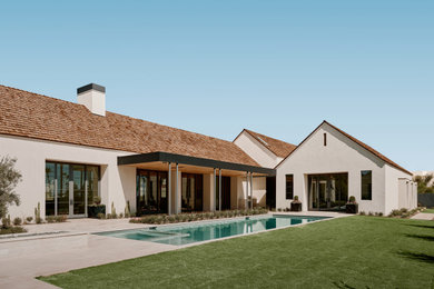 Example of a farmhouse white two-story stucco exterior home design in Phoenix with a shingle roof and a brown roof