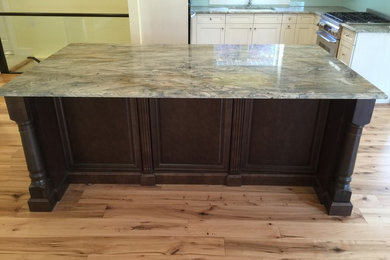Example of a mid-sized eclectic light wood floor kitchen design in Calgary with an undermount sink, quartzite countertops, stainless steel appliances, an island and glass sheet backsplash