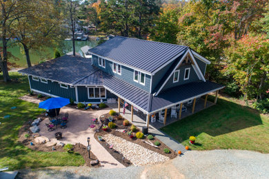 Example of a huge arts and crafts blue two-story concrete fiberboard and board and batten exterior home design in Other with a metal roof and a black roof