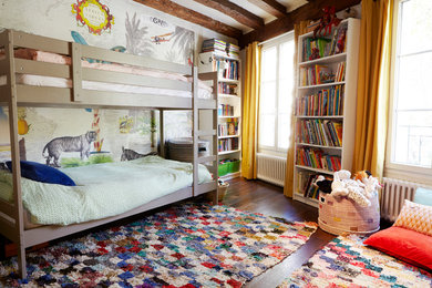Photo of an eclectic gender-neutral kids' bedroom for kids 4-10 years old in Paris with multi-coloured walls, dark hardwood floors and brown floor.