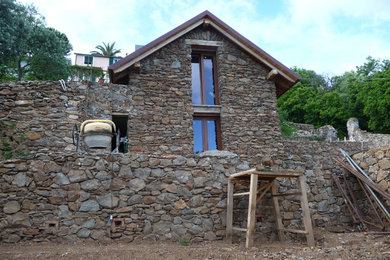 Esempio della facciata di una casa country a due piani con rivestimento in pietra e tetto a capanna