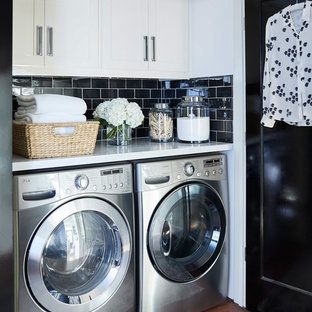 Modelo de armario lavadero lineal, tradicional renovado, pequeño, con puertas de armario blancas, encimera de mármol, lavadora y secadora juntas, armarios estilo shaker, suelo de madera oscura, suelo marrón, encimeras blancas y paredes blancas