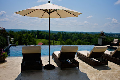 Large trendy backyard stamped concrete and rectangular infinity pool fountain photo in Philadelphia