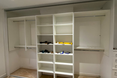 Diseño de armario y vestidor minimalista de tamaño medio con a medida, armarios con paneles lisos y puertas de armario blancas