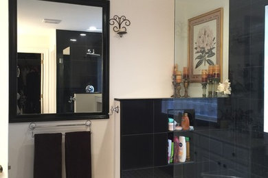 Mid-sized minimalist master black tile and porcelain tile porcelain tile doorless shower photo in New York with raised-panel cabinets, medium tone wood cabinets, white walls and quartzite countertops
