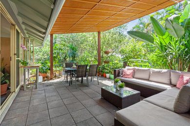 Design ideas for a mid-sized tropical backyard patio in Sunshine Coast with concrete pavers and an awning.