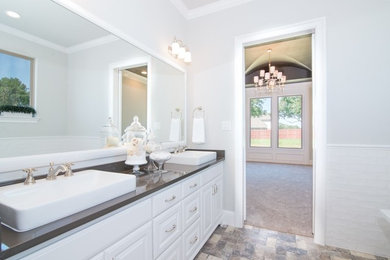 Inspiration for a mid-sized transitional master bathroom in Dallas with raised-panel cabinets, white cabinets, white tile, subway tile, granite benchtops, a freestanding tub, a corner shower, a two-piece toilet, white walls, ceramic floors, a vessel sink, beige floor and a hinged shower door.