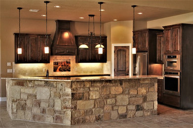 Large elegant l-shaped porcelain tile and beige floor eat-in kitchen photo in Other with an undermount sink, raised-panel cabinets, dark wood cabinets, granite countertops, beige backsplash, stone tile backsplash, stainless steel appliances, an island and multicolored countertops