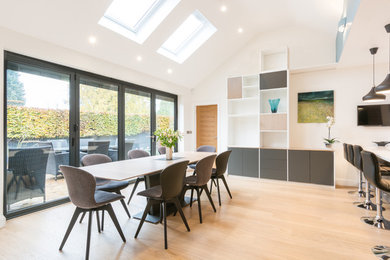 Design ideas for a mid-sized contemporary open plan dining in Hertfordshire with white walls, medium hardwood floors, a hanging fireplace and a metal fireplace surround.