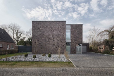 Inspiration for a contemporary two-storey brick brown house exterior in Bremen with a flat roof.