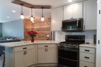 Open concept kitchen - mid-sized country u-shaped light wood floor and beige floor open concept kitchen idea in Other with a drop-in sink, shaker cabinets, laminate countertops, white backsplash, subway tile backsplash, a peninsula, white cabinets, stainless steel appliances and gray countertops
