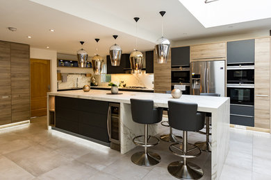 Large modern l-shaped open plan kitchen in Surrey with an integrated sink, flat-panel cabinets, grey cabinets, composite countertops, white splashback, slate splashback, stainless steel appliances, porcelain flooring, an island and grey floors.