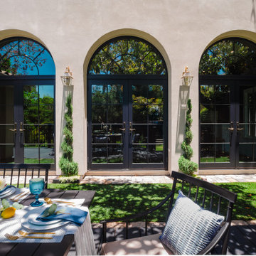 Mediterranean Patio Dining Area with Arched Black French Doors and Stucco Exteri