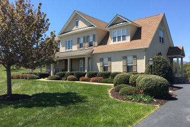 Example of a mid-sized classic beige two-story stone exterior home design in Other with a mixed material roof