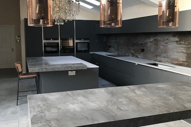 Inspiration for a large contemporary eat-in kitchen in London with a single-bowl sink, flat-panel cabinets, grey cabinets, solid surface benchtops, stone slab splashback, cement tiles, multiple islands, grey floor and grey benchtop.