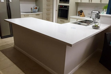 This is an example of a mid-sized modern l-shaped kitchen in Perth with quartz benchtops.