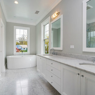 Exemple d'une grande douche en alcôve principale chic avec un placard avec porte à panneau encastré, des portes de placard blanches, une baignoire indépendante, un WC séparé, un carrelage gris, un carrelage blanc, des dalles de pierre, un mur gris, un sol en marbre, un lavabo encastré, un plan de toilette en stéatite, un sol multicolore et une cabine de douche à porte battante.