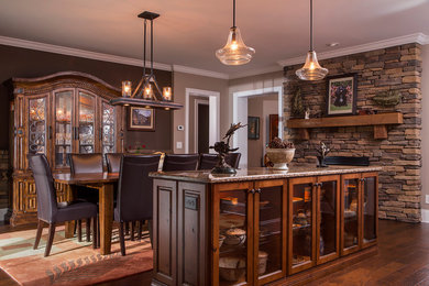 Inspiration for a large transitional kitchen/dining combo in Other with brown walls, dark hardwood floors, a standard fireplace, a stone fireplace surround and brown floor.