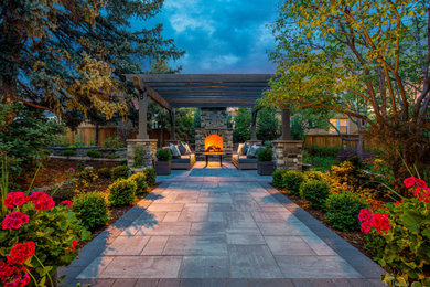 Foto de patio clásico grande en patio trasero con chimenea, adoquines de hormigón y pérgola