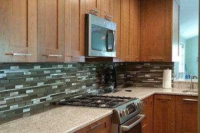 Mid-sized transitional u-shaped light wood floor eat-in kitchen photo in Chicago with an undermount sink, shaker cabinets, medium tone wood cabinets, granite countertops, multicolored backsplash, glass tile backsplash, stainless steel appliances and an island