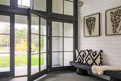 Example of a beach style gray floor entryway design in Boston with white walls and a glass front door