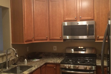 Example of a small classic u-shaped enclosed kitchen design in DC Metro with an undermount sink, recessed-panel cabinets, light wood cabinets, granite countertops and stainless steel appliances