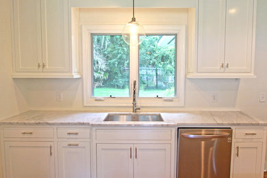 Mid-sized transitional u-shaped dark wood floor and brown floor eat-in kitchen photo in Jacksonville with a single-bowl sink, shaker cabinets, white cabinets, marble countertops, stainless steel appliances and a peninsula
