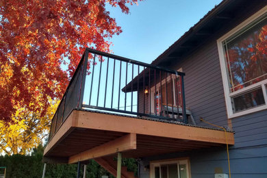 Example of a mid-sized minimalist backyard second story metal railing deck design in Seattle with an awning