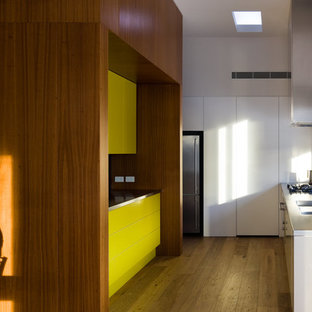 Mid-sized contemporary kitchen pantry photos - Mid-sized trendy l-shaped medium tone wood floor kitchen pantry photo in Adelaide with an integrated sink, flat-panel cabinets, medium tone wood cabinets, stainless steel countertops, yellow backsplash, glass tile backsplash, stainless steel appliances and no island