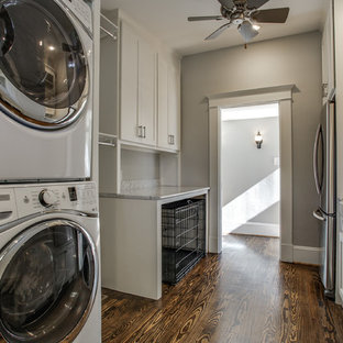 ダラスの大きいトランジショナルスタイルのおしゃれな家事室 (エプロンフロントシンク、シェーカースタイル扉のキャビネット、白いキャビネット、大理石カウンター、グレーの壁、濃色無垢フローリング、上下配置の洗濯機・乾燥機) の写真