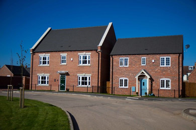 Brown modern brick detached house in West Midlands with three floors, a half-hip roof and a tiled roof.