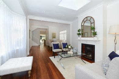 Photo of a contemporary formal open concept living room in Sydney with white walls, dark hardwood floors, a standard fireplace and a plaster fireplace surround.