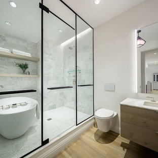 Example of a trendy master white tile and marble tile light wood floor and beige floor bathroom design in New York with flat-panel cabinets, light wood cabinets, a wall-mount toilet, white walls and an undermount sink