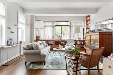 Inspiration for a mid-sized contemporary open concept medium tone wood floor and brown floor living room library remodel in New York with gray walls, no fireplace and a concealed tv