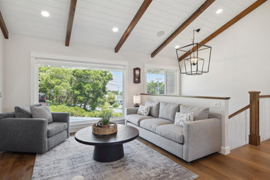 Example of a transitional open concept medium tone wood floor, brown floor and vaulted ceiling living room design in San Francisco with white walls