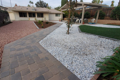 This is an example of a large transitional drought-tolerant and full sun backyard concrete paver and stone fence retaining wall landscape in Los Angeles for spring.