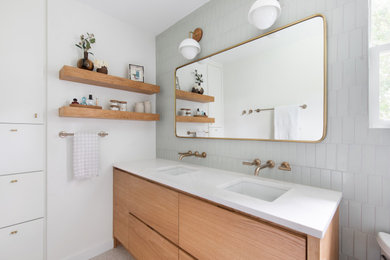 Alcove shower - mid-sized transitional 3/4 green tile and porcelain tile beige floor and double-sink alcove shower idea in Austin with flat-panel cabinets, light wood cabinets, a one-piece toilet, white walls, an undermount sink, quartz countertops, a hinged shower door, white countertops and a built-in vanity