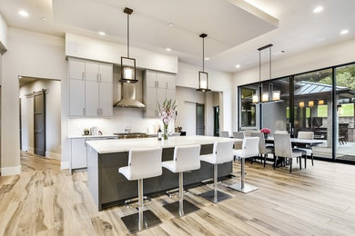 Large minimalist galley light wood floor and brown floor eat-in kitchen photo in Austin with flat-panel cabinets, gray cabinets, marble countertops, white backsplash, subway tile backsplash, stainless steel appliances, an island and white countertops