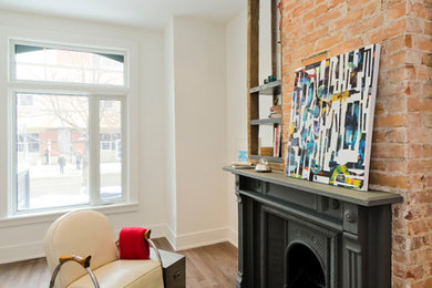 Small eclectic open concept living room in Toronto with a library, white walls, medium hardwood floors, a brick fireplace surround and no tv.
