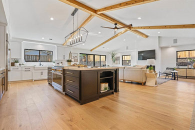 Huge farmhouse u-shaped light wood floor, brown floor and exposed beam kitchen pantry photo in San Francisco with a farmhouse sink, recessed-panel cabinets, quartz countertops, white backsplash, subway tile backsplash, stainless steel appliances, an island and multicolored countertops