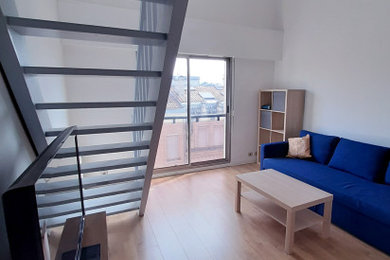 Idée de décoration pour une salle de séjour mansardée ou avec mezzanine design de taille moyenne avec un mur blanc, parquet clair, aucune cheminée, un téléviseur indépendant et un sol beige.