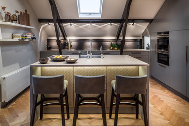 Example of a small trendy galley light wood floor and beige floor open concept kitchen design in Amsterdam with a drop-in sink, flat-panel cabinets, gray cabinets, gray backsplash, an island and colored appliances