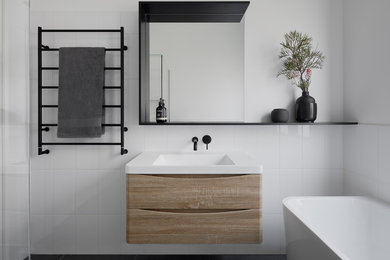 Design ideas for a mid-sized modern kids bathroom in Melbourne with raised-panel cabinets, light wood cabinets, a freestanding tub, a corner shower, a one-piece toilet, white tile, ceramic tile, white walls, cement tiles, an integrated sink, solid surface benchtops, grey floor, a hinged shower door and white benchtops.