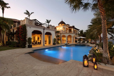 Example of a huge tuscan backyard stone and custom-shaped natural pool design in Miami