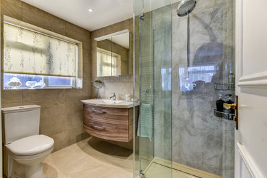 Design ideas for a small shower room bathroom in Sussex with medium wood cabinets, a corner shower, a two-piece toilet, beige tiles, ceramic tiles, beige walls, vinyl flooring, a built-in sink, beige floors, a hinged door, feature lighting, a single sink and a floating vanity unit.