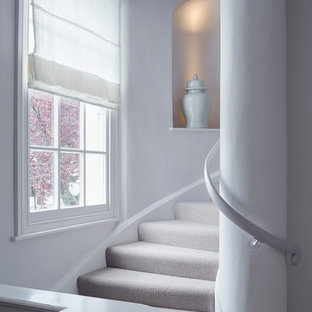 Photo of a traditional carpeted curved wood railing staircase in Gloucestershire with carpeted risers.
