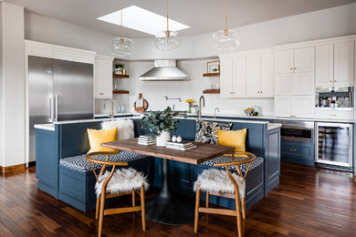Inspiration for a transitional l-shaped medium tone wood floor and brown floor eat-in kitchen remodel in Sacramento with recessed-panel cabinets, white cabinets, white backsplash, stainless steel appliances, an island and white countertops
