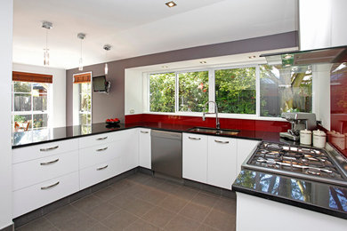 Inspiration for a mid-sized contemporary u-shaped eat-in kitchen in Christchurch with an undermount sink, quartz benchtops, red splashback, glass sheet splashback, stainless steel appliances and ceramic floors.