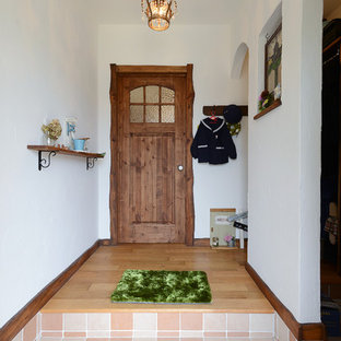 他の地域の片開きドア地中海スタイルのおしゃれな玄関ホール (白い壁、濃色木目調のドア、オレンジの床) の写真